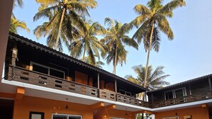 A two-story building with an outdoor swimming pool, surrounded by palm trees. - OZIBA BEACH RESORT (Arambol)