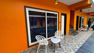 A room with a large sliding glass door, white chairs, and a small table.