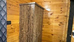 A wooden cabin interior with a wardrobe, a patterned curtain, and a tiled floor. - OZIBA BEACH RESORT (Arambol)