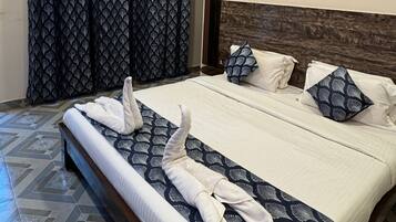 A hotel room with a bed, curtains, a ceiling fan, and a patterned floor.