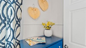 A room with a blue dresser, a white vase with yellow flowers, and two heart-shaped wall decorations. - Jax Bch Home 3/2 w/Pets (Jacksonville Beach)