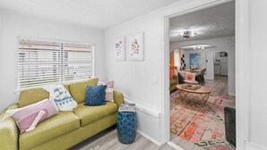 A living room with a green sofa, a coffee table, and a patterned rug. - Jax Bch Home 3/2 w/Pets (Jacksonville Beach)