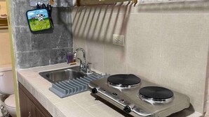 Una cocina compacta con un lavamanos, dos hornillas y una pequeña encimera.