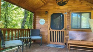 A wooden cabin with a porch, a welcome sign, a bench, and a window. - Asheboro 1BR Cabin Near NC Zoo | Loft & Water View (Asheboro)