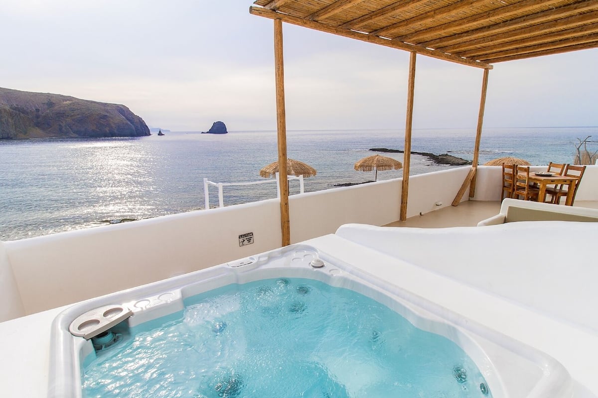 A hot tub on a balcony with a view of the sea and cliffs.