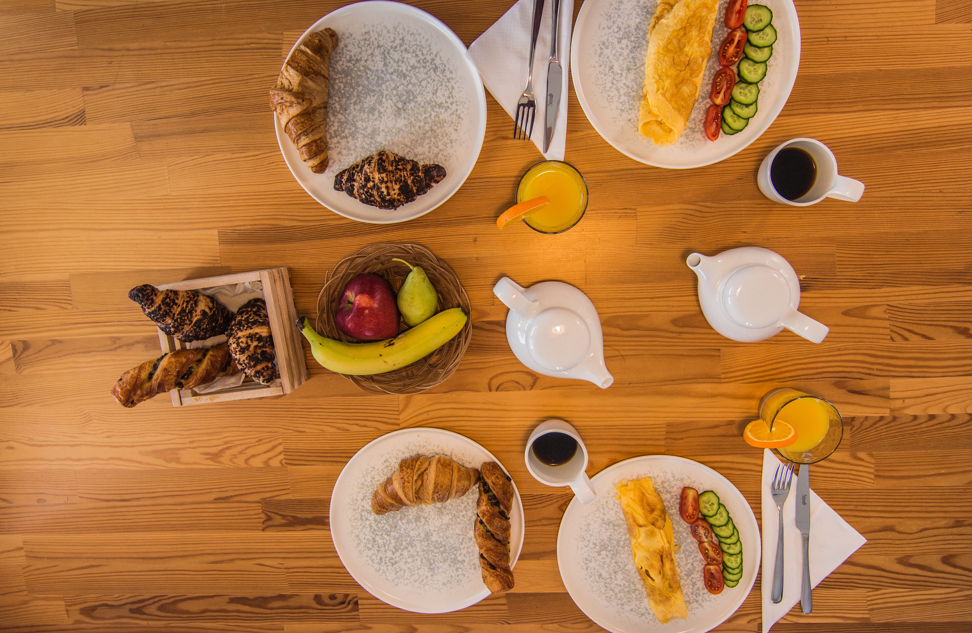 A breakfast setting with various food items and drinks on a wooden table.