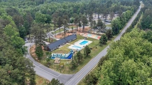 An aerial view of a property with a swimming pool, a covered area, and a road.