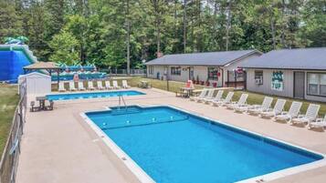 A swimming pool with lounge chairs and a water slide in the background.