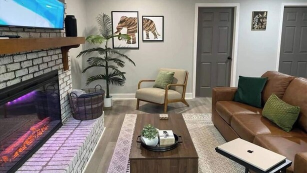 A living room with a fireplace, a sofa, a chair, a coffee table, and a TV on the wall.