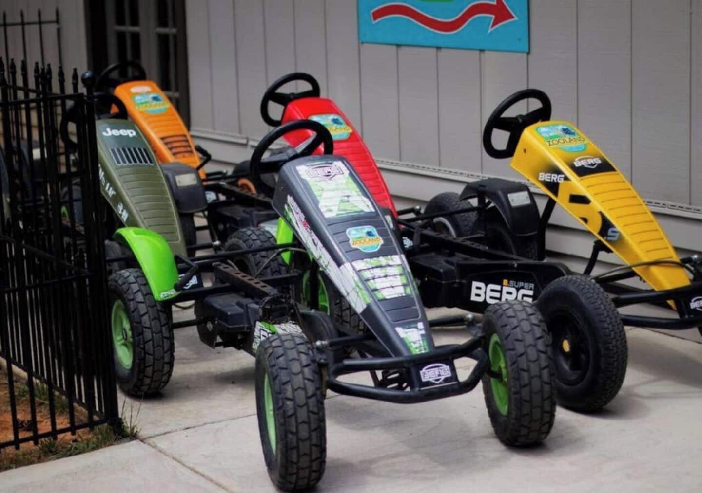 Three go-karts parked in front of a building with a blue sign.