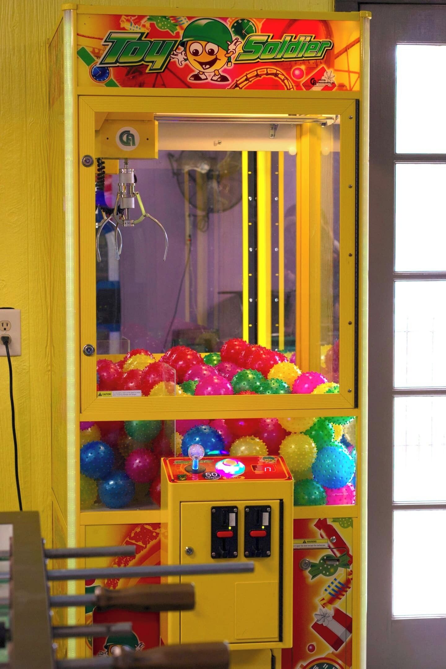 A claw machine with colorful balls and a 'Toy Soldier' theme.