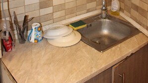 A kitchen with a sink, a cup, and a dish rack. - Renovated Studio Olympiados (Thessaloniki)