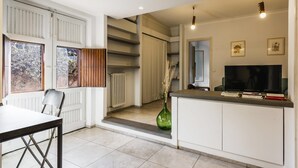 A modern kitchen with a dining area, white cabinetry, a large window, and a television. - Euphorbia Apartment 2 in Catania by Wonderful Italy (Catania)