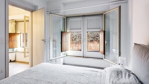 A bedroom with a large bed, a window with a view of the outdoors, and a door leading to another room. - Euphorbia Apartment 2 in Catania by Wonderful Italy (Catania)