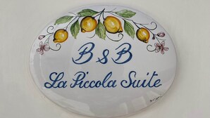 Une plaque décorative portant l’inscription « B&B La Piccola Suite » et illustrée de motifs de citrons et de feuilles.