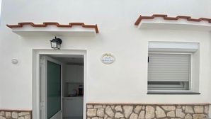 Un bâtiment doté d’un mur en pierre, d’une porte donnant sur une cuisine et d’une fenêtre avec un volet.