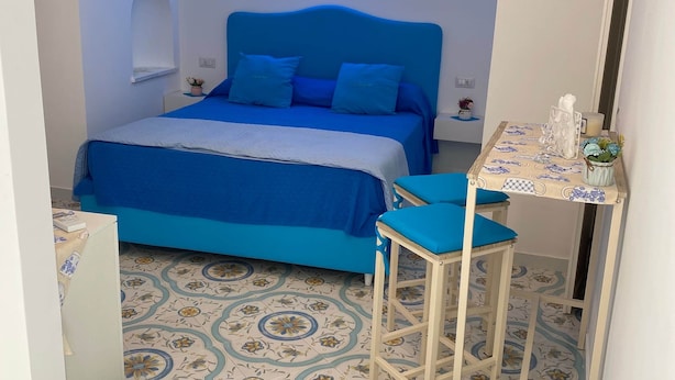 Une chambre à coucher avec un lit, une table de chevet, une chaise et un panneau lumineux au néon.