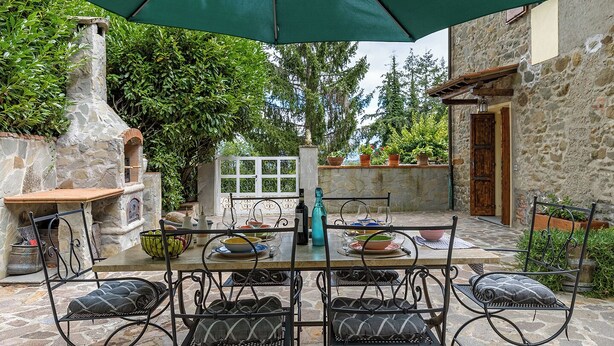 An outdoor patio with stone walls, a table set for dining, and a stone oven. - Chianti Villa Chicco, private swimming pool with large garden, bbq, car parking (Province of Florence)