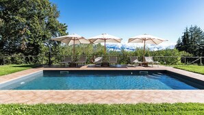 A rectangular swimming pool with a tiled deck, surrounded by lounge chairs and umbrellas. - Chianti Villa Chicco, private swimming pool with large garden, bbq, car parking (Province of Florence)