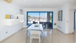 Un comedor moderno con una mesa grande y sillas, vistas al exterior y una pared de piedra.