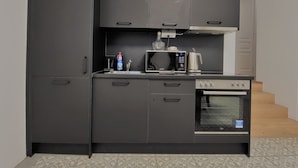 Eine kompakte Küche mit Kühlschrank, Mikrowelle, Wasserkocher und Backofen.