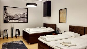 Ein modernes Hotelzimmer mit zwei Betten, einem großen Stadtbildgemälde, einem schwarzen Schrank und einer schwarzen Stehlampe.