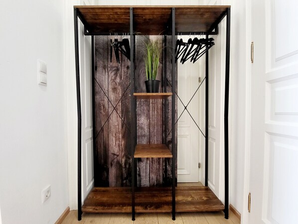 Ein Zimmer mit Holzboden, einer schwarzen Metallregaleinheit und einer rustikalen Wandverkleidung.