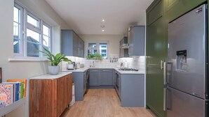 A modern kitchen with grey cabinets, a wooden countertop, and a stainless steel refrigerator. - 2 Bedroom Apartment - 200m From Richmond Park (Kingston Upon Thames)
