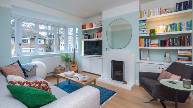 A modern living room with a fireplace, a bookshelf, and a large window. - 2 Bedroom Apartment - 200m From Richmond Park (Kingston Upon Thames)