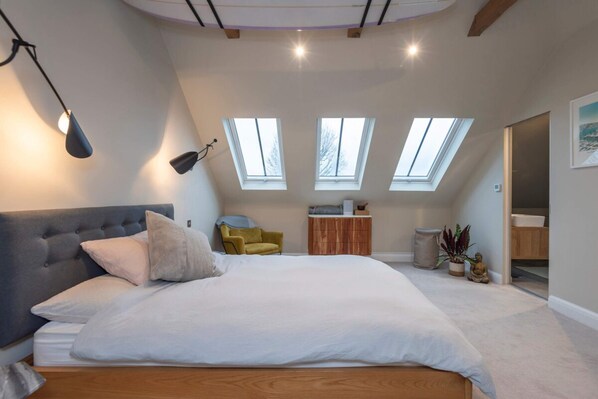 A bedroom with a large bed, a headboard, a desk, a chair, and skylights. - 2 Bedroom Apartment - 200m From Richmond Park (Kingston Upon Thames)