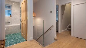 A modern interior with a glass door leading to a bathroom, a wooden staircase, and a hallway with a patterned floor. - 2 Bedroom Apartment - 200m From Richmond Park (Kingston Upon Thames)