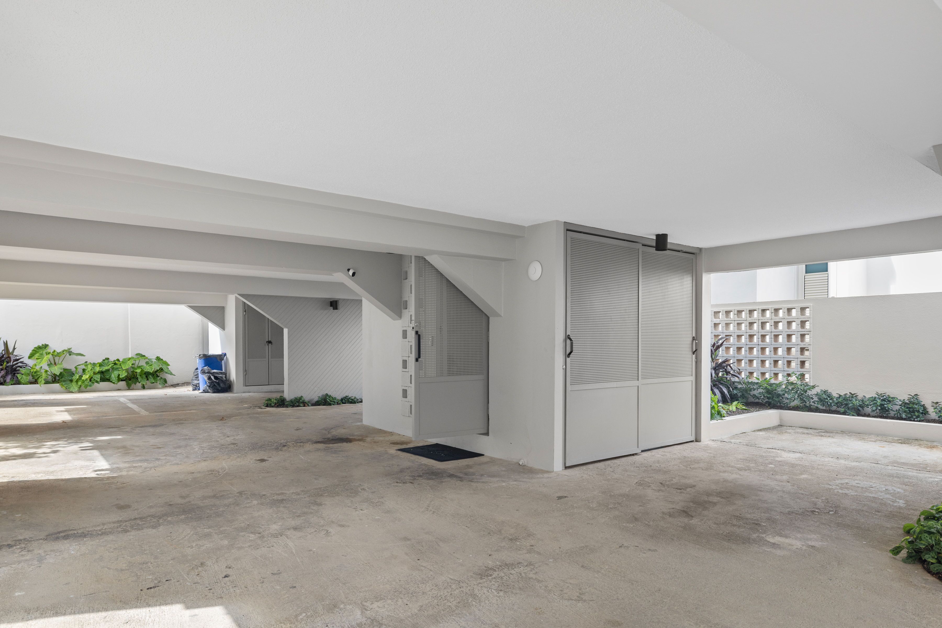 A spacious, modern indoor area with a concrete floor, a staircase, and a door leading to another room.