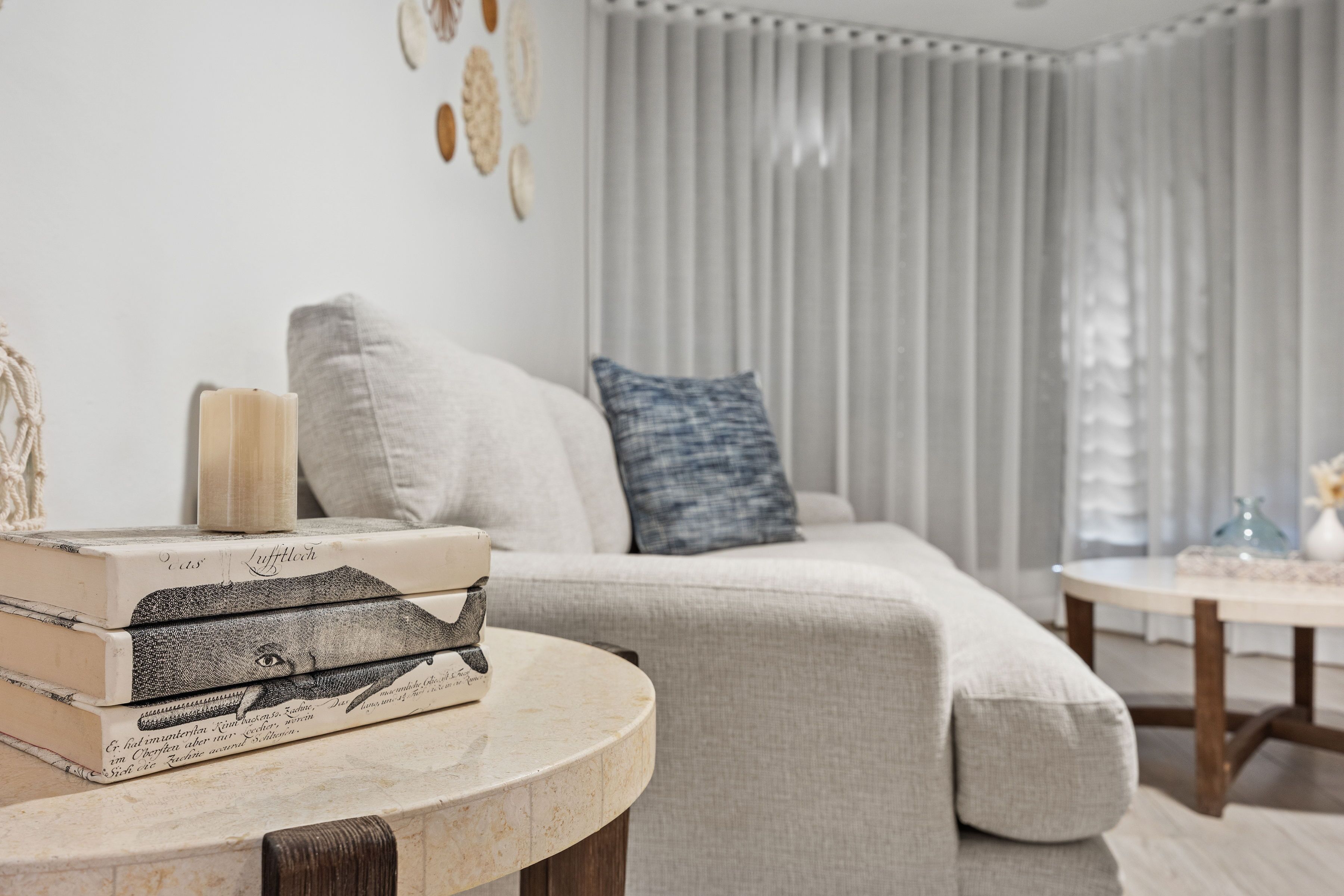 A living room with a sofa, a round table, and a stack of books.