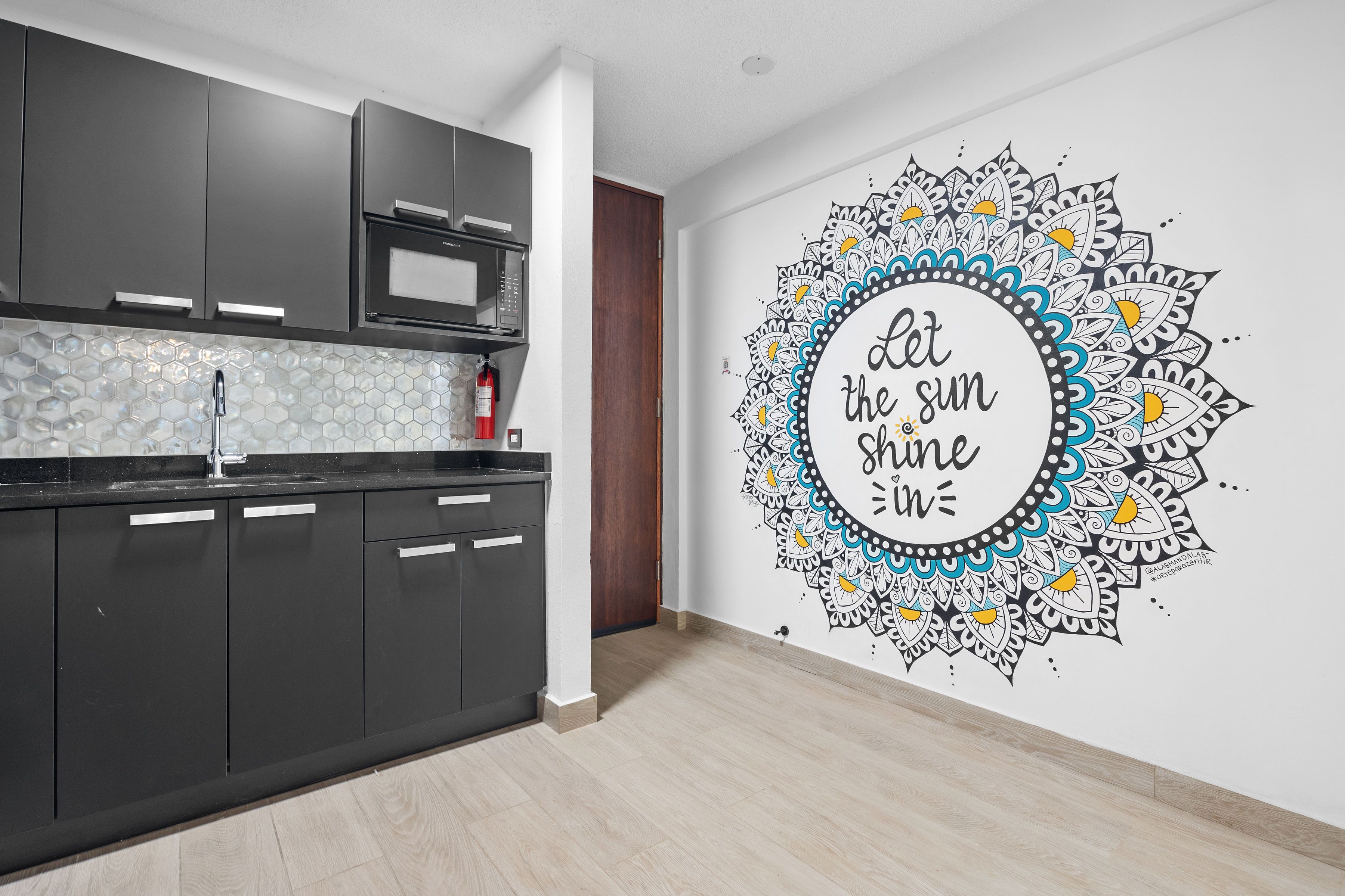 A modern kitchen with dark cabinets, a microwave, and a hexagonal backsplash.