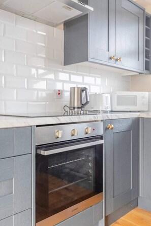 A kitchen with grey cabinets, a stainless steel oven, a microwave, and a coffee maker.