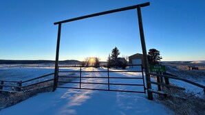 A metal gate with a sign reading "8418 HWY 41" in a snowy landscape with a clear sky. - Cozy cabin in charming Cypress Hills with WiFi (Cypress County)