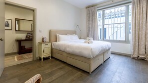 A bedroom with a large bed, bedside tables, a dresser, and a window with curtains. - Elegant 2BD Flat 5 Mins to Kensington Gardens! (London)
