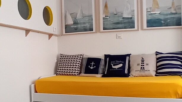 A bedroom with a colorful checkered rug, a bed with a yellow blanket, and three framed paintings of sailboats on the wall. - Dinard Hyper Centre 400m Plages Beau Studio Wifi (Dinard)