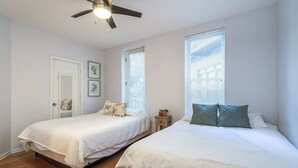 Un dormitorio con dos camas, un ventilador de techo y una ventana con persianas.