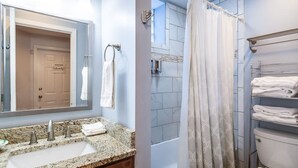 Un baño con lavamanos de granito, espejo, ducha con cortina estampada y inodoro con toallero.