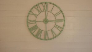 A large green clock mounted on a plain wall. - Le Scalette Apartment - G (Osimo)