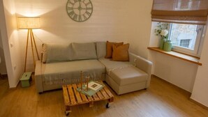 A cozy living room with a sofa, a coffee table, a lamp, and a clock on the wall. - Le Scalette Apartment - G (Osimo)
