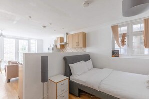 A modern bedroom with a bed, a bedside table, a wardrobe, and a window with curtains. - Studio W/private Patio Heart of Brixton, London! (London)