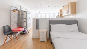 Quarto moderno com cama, cadeira, guarda-roupa e escrivaninha.