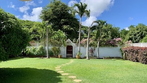 A well-maintained garden with a clear pathway leading to a white building with a red door.