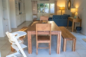 A dining area with a wooden table and chairs, a sofa, and a lamp on a side table.