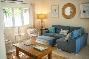 A living room with a sofa, a chair, a coffee table, a lamp, and framed artwork on the wall.