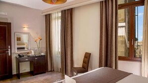 A hotel room with a bed, a desk with a laptop, a chair, a mirror, and a window with curtains. - Basilio Veneto Rome (Rome)