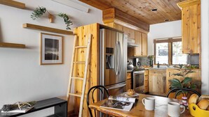 A modern kitchen with wooden cabinets, stainless steel appliances, and a dining area with a wooden table and chairs. - Grand Teton View!!! Jackson Hole's Spring Creek Lookout (Jackson)