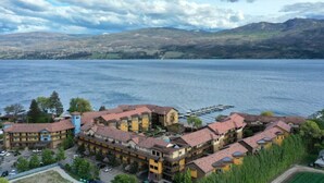 A hotel with multiple buildings, a dock, and a lake with mountains in the background.
